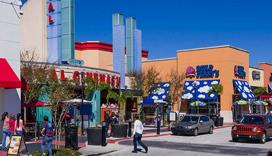 Daytime exterior photo of The Loop. Shoppers walk around outside of RPX Regal Cinemas, Ben & Jerry's, and Jimmy John's. Kissimmee, Florida.