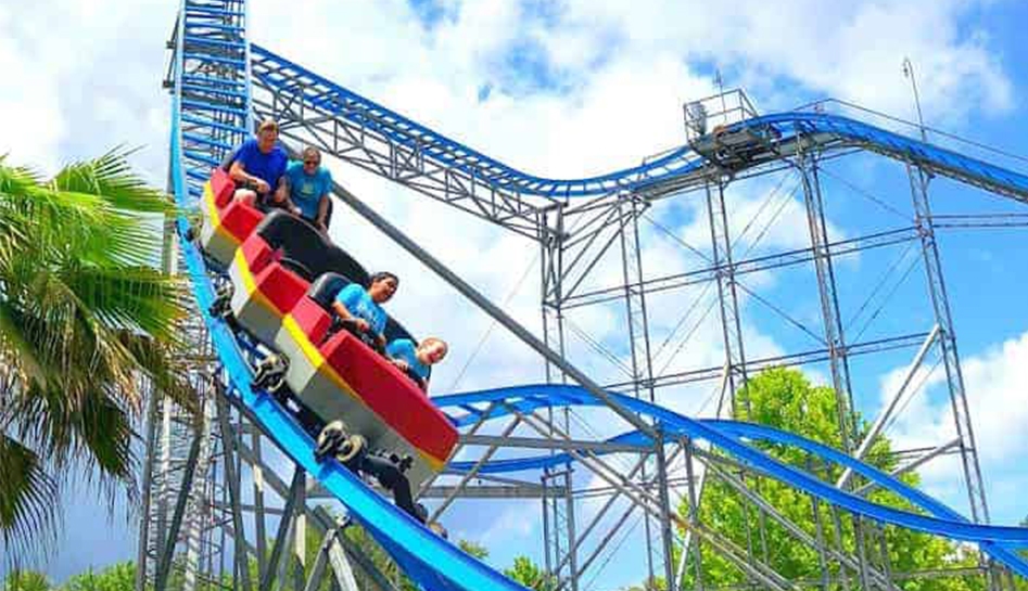 Guests on a rollercoaster going downward at Fun Spot Kissimmee. Daytime photo. Kissimmee, Florida.