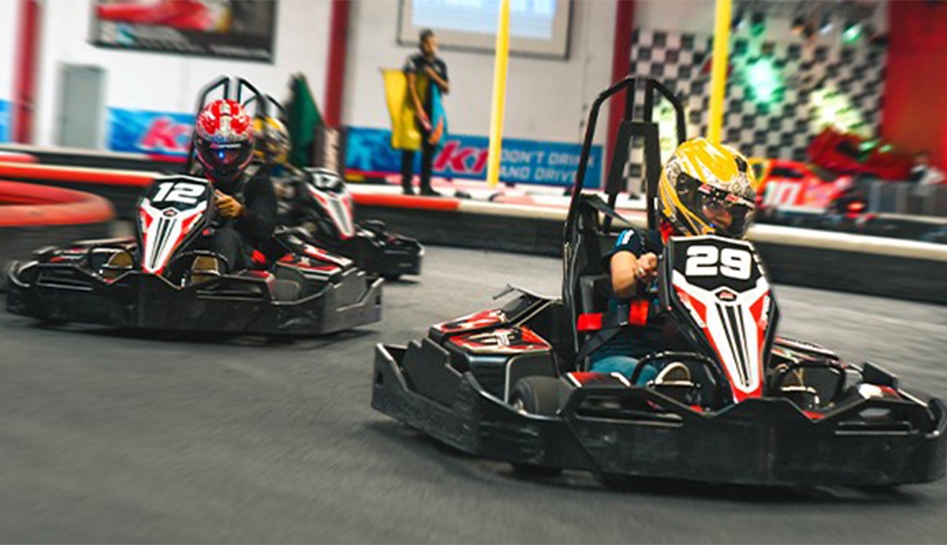 Two guests racing one another on an indoor track in go-karts at K1 Speed. Orlando, Florida.