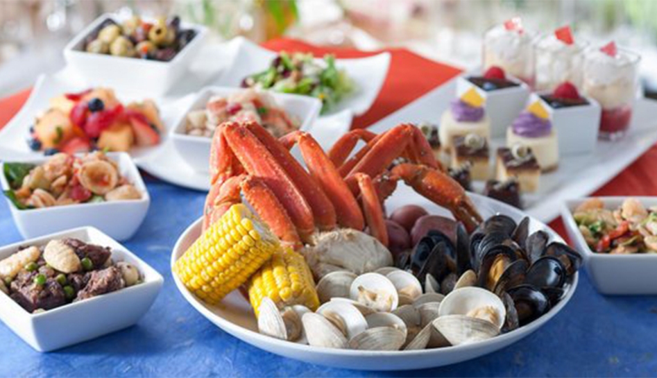 Assortment of food items including crab legs, corn, clams, and others in the background at Cape May Cafe inside of Walt Disney World® Resort. Lake Buena Vista, Florida.