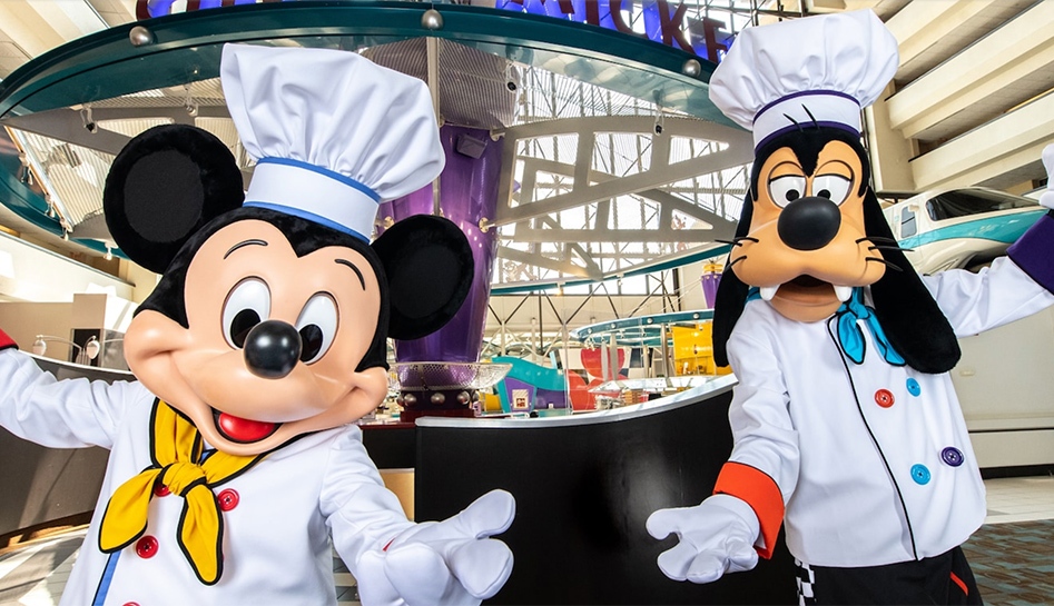 Chef Mickey Mouse (left) and Chef Goofy (right) pose with arms spread out for a photo inside of Chef Mickey's buffet at The Contemporary Resort. Walt Disney World® Resort. Lake Buena Vista, Florida.