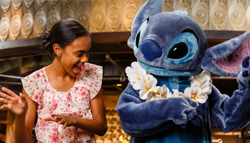 Teen girl (left) dancing the hula dance with Stitch (right) character as he wears a lei at the 'Ohana buffet restaurant at Walt Disney World® Resort. Lake Buena Vista, Florida.